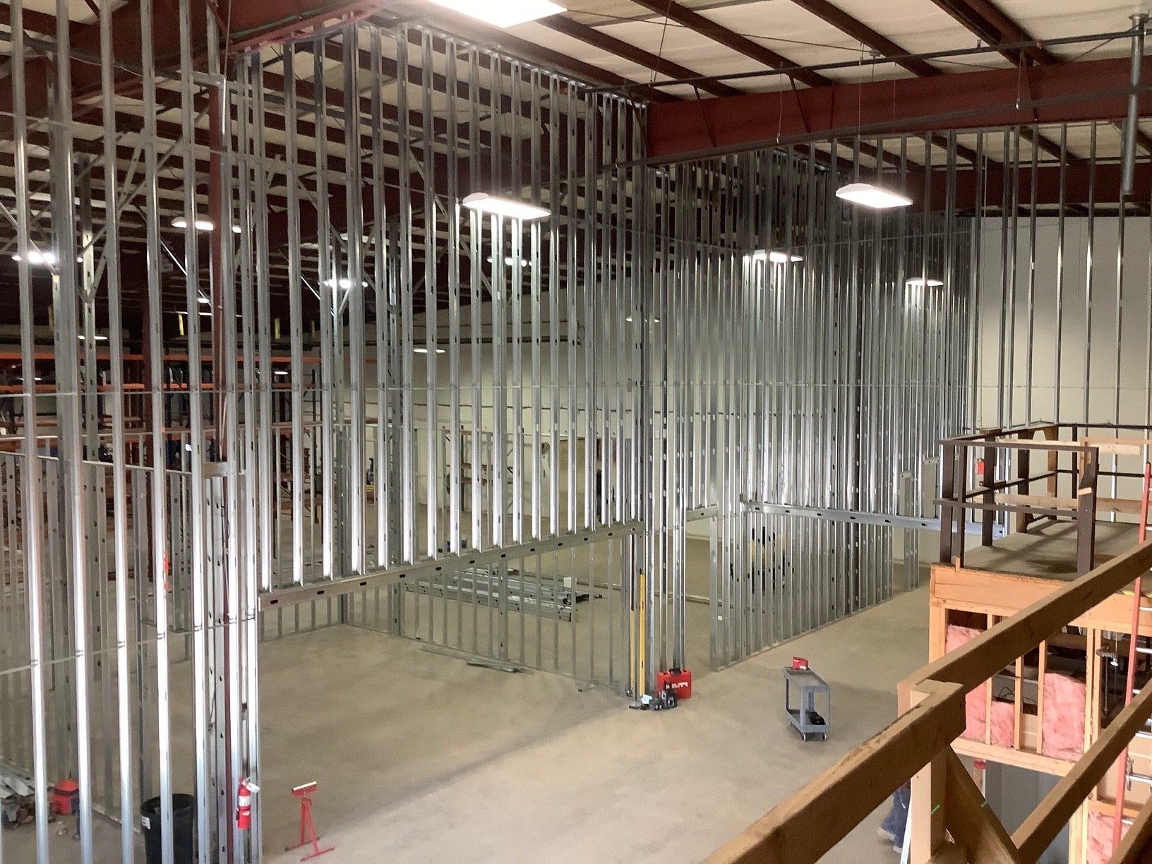 Metal studs framing interior walls in a large warehouse. Construction in progress.
