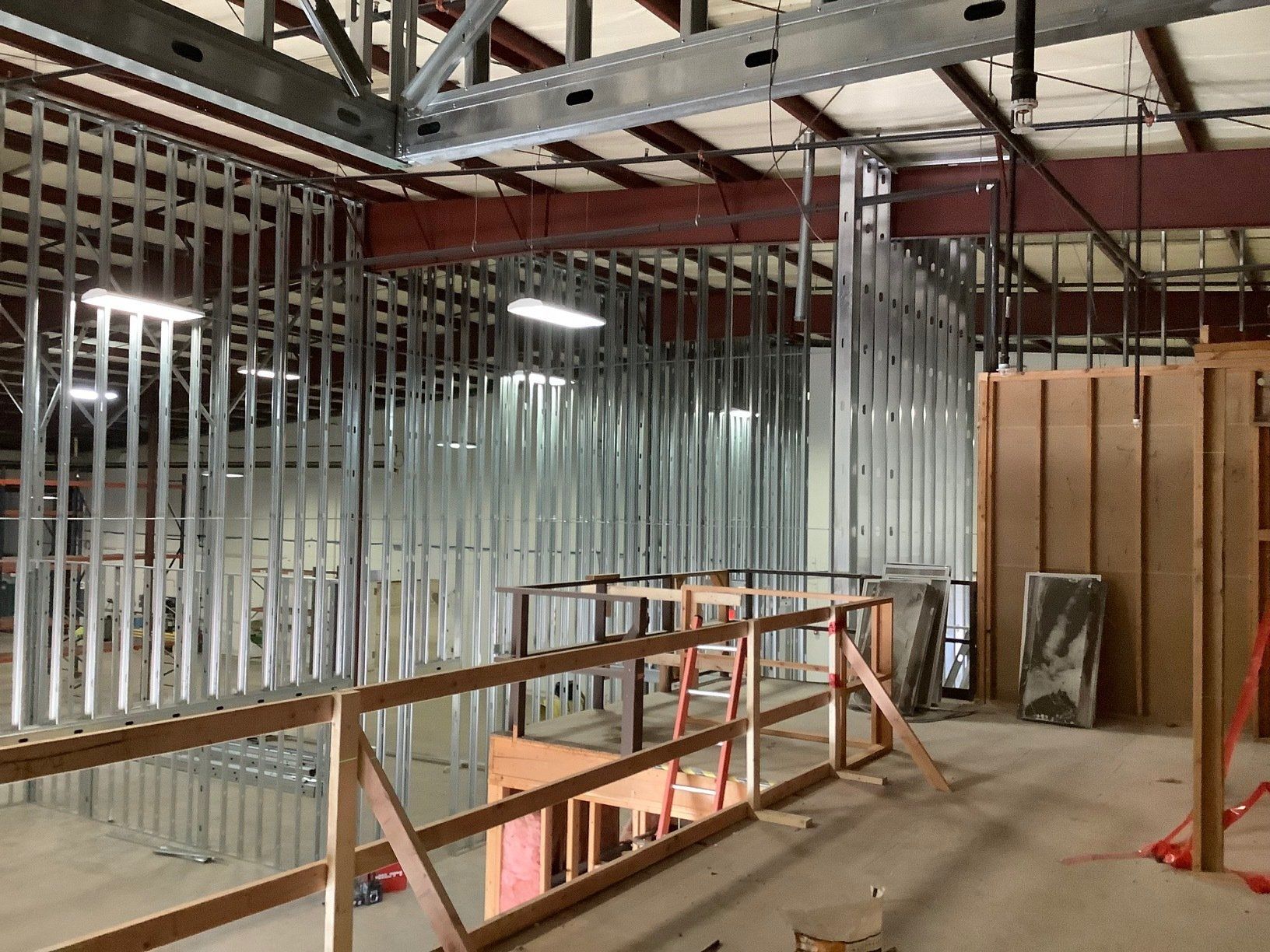 Interior construction: metal stud framing, wooden safety railing, unfinished walls and ceiling.