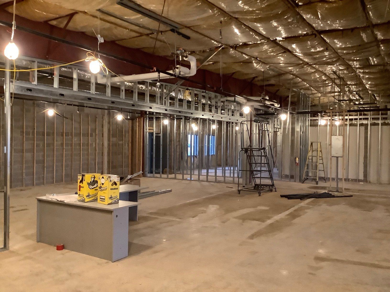 Interior under construction: metal studs, exposed wiring, and concrete floor.