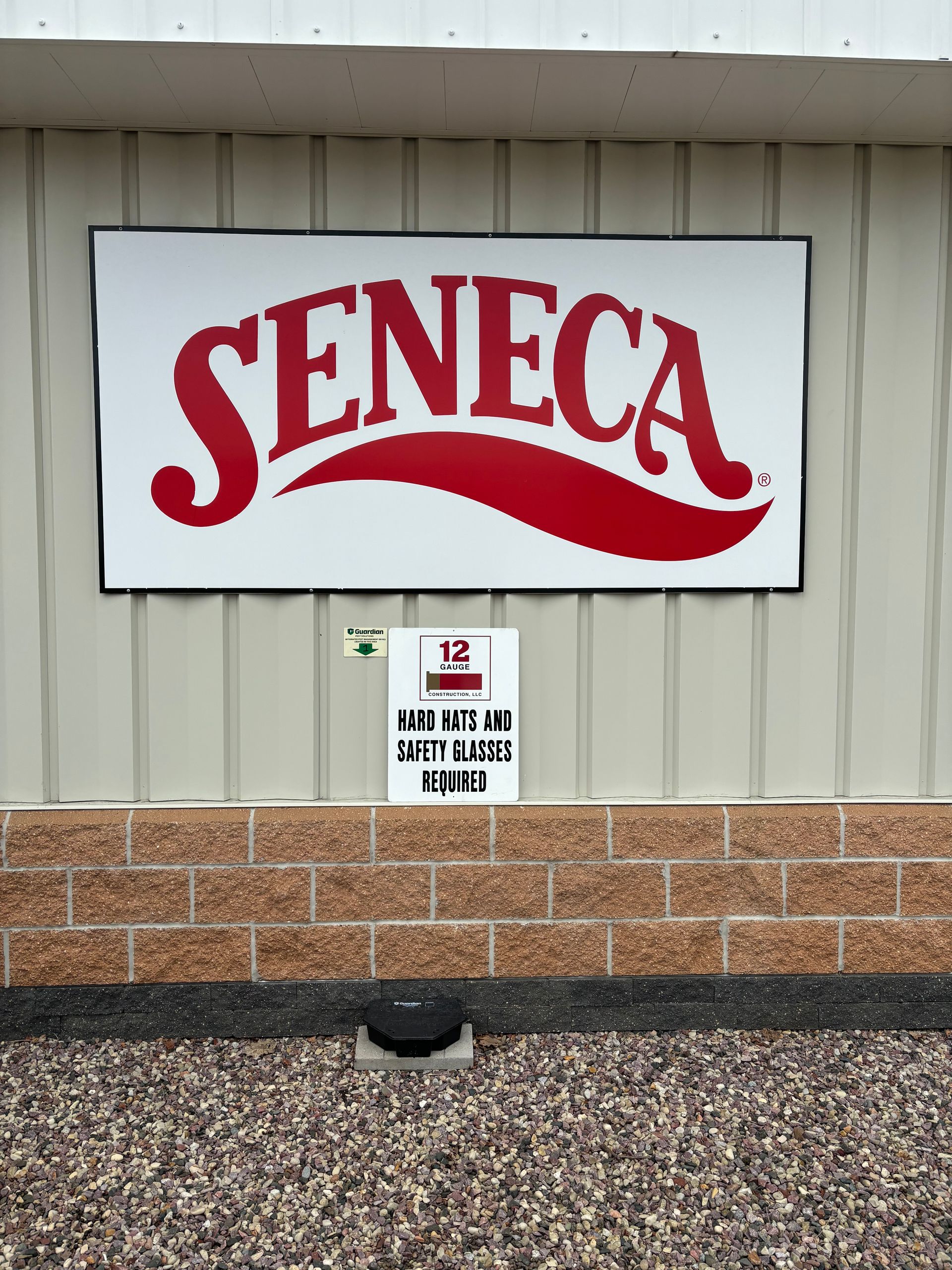 Seneca sign in red lettering on a white background, mounted on a tan building.