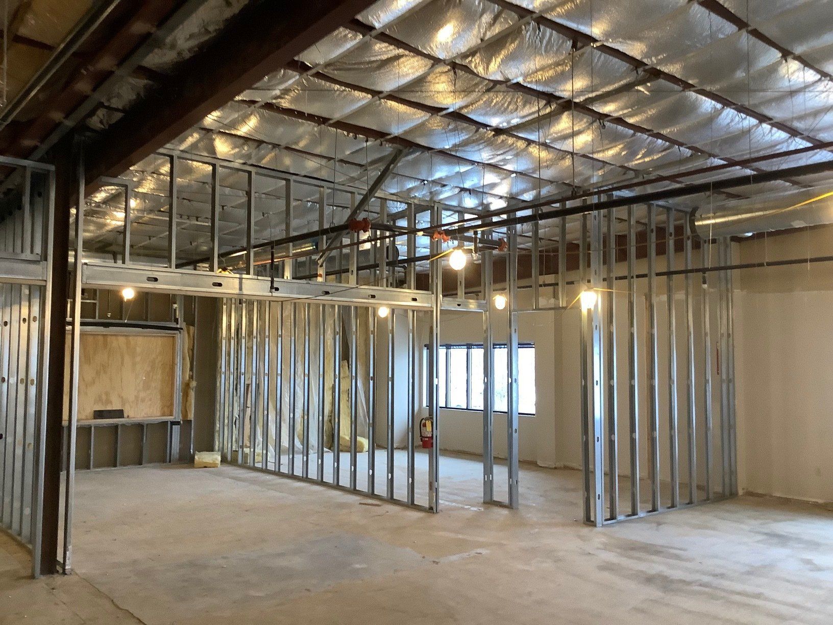 Interior of a commercial space under construction with metal framing for walls and ceiling.