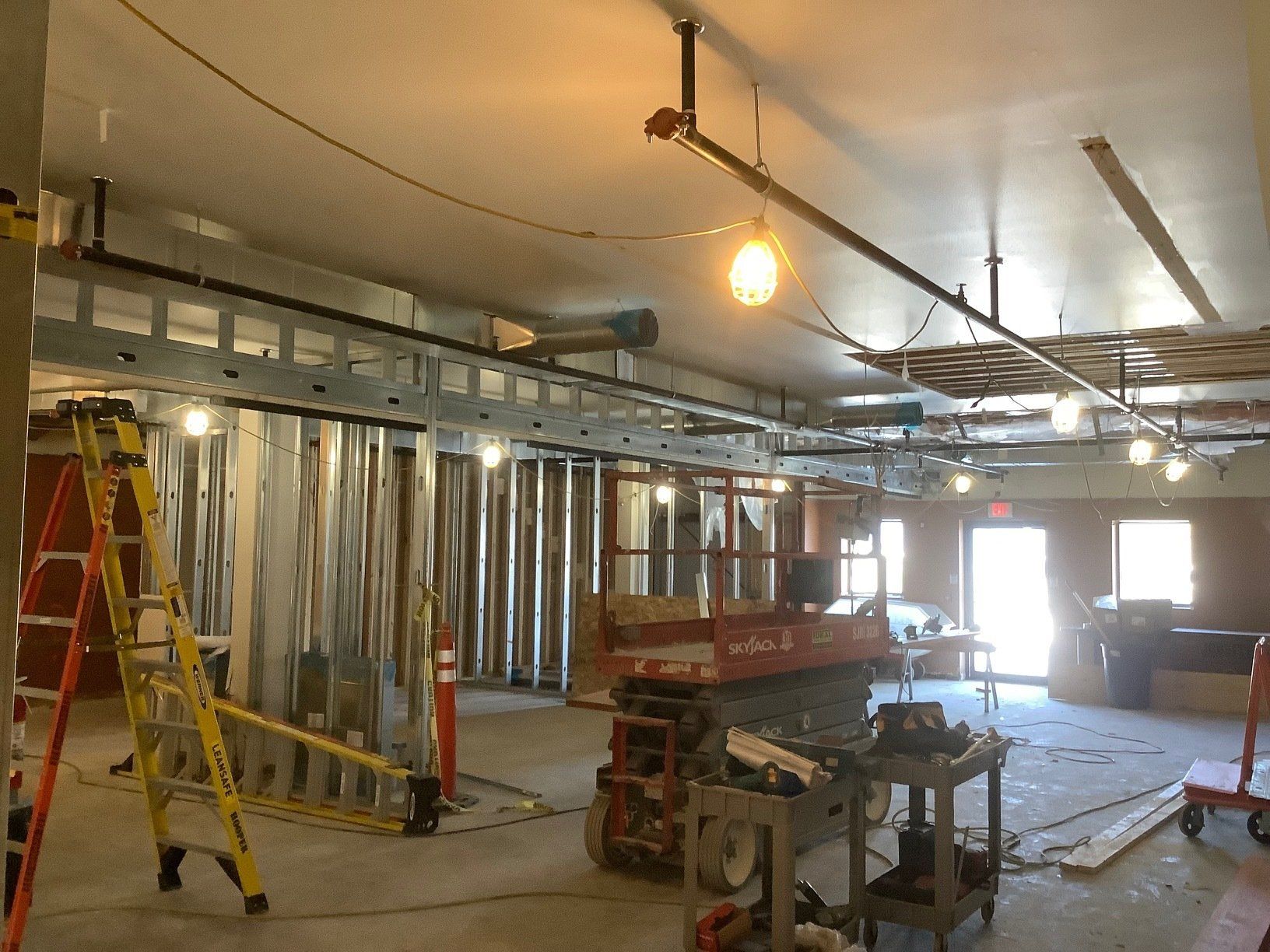 Interior construction site with metal framing, exposed wiring, and tools.