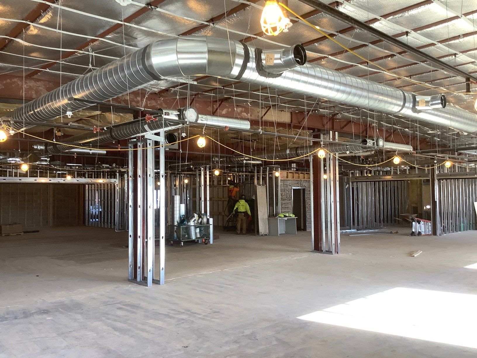 Interior construction of a commercial space, metal studs, HVAC ductwork visible, unfinished.