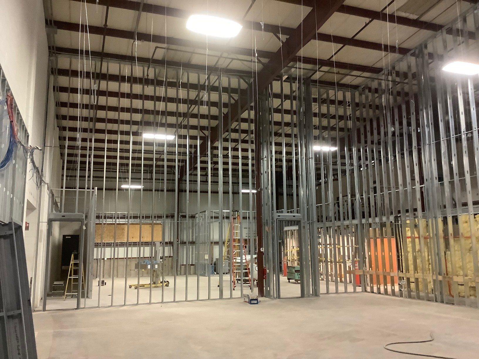 Interior view of a building under construction, metal framing for walls and ceiling, concrete floor.