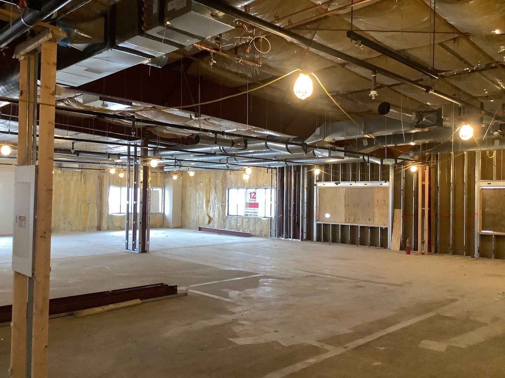 Interior construction site with exposed framing, ductwork, and insulation.