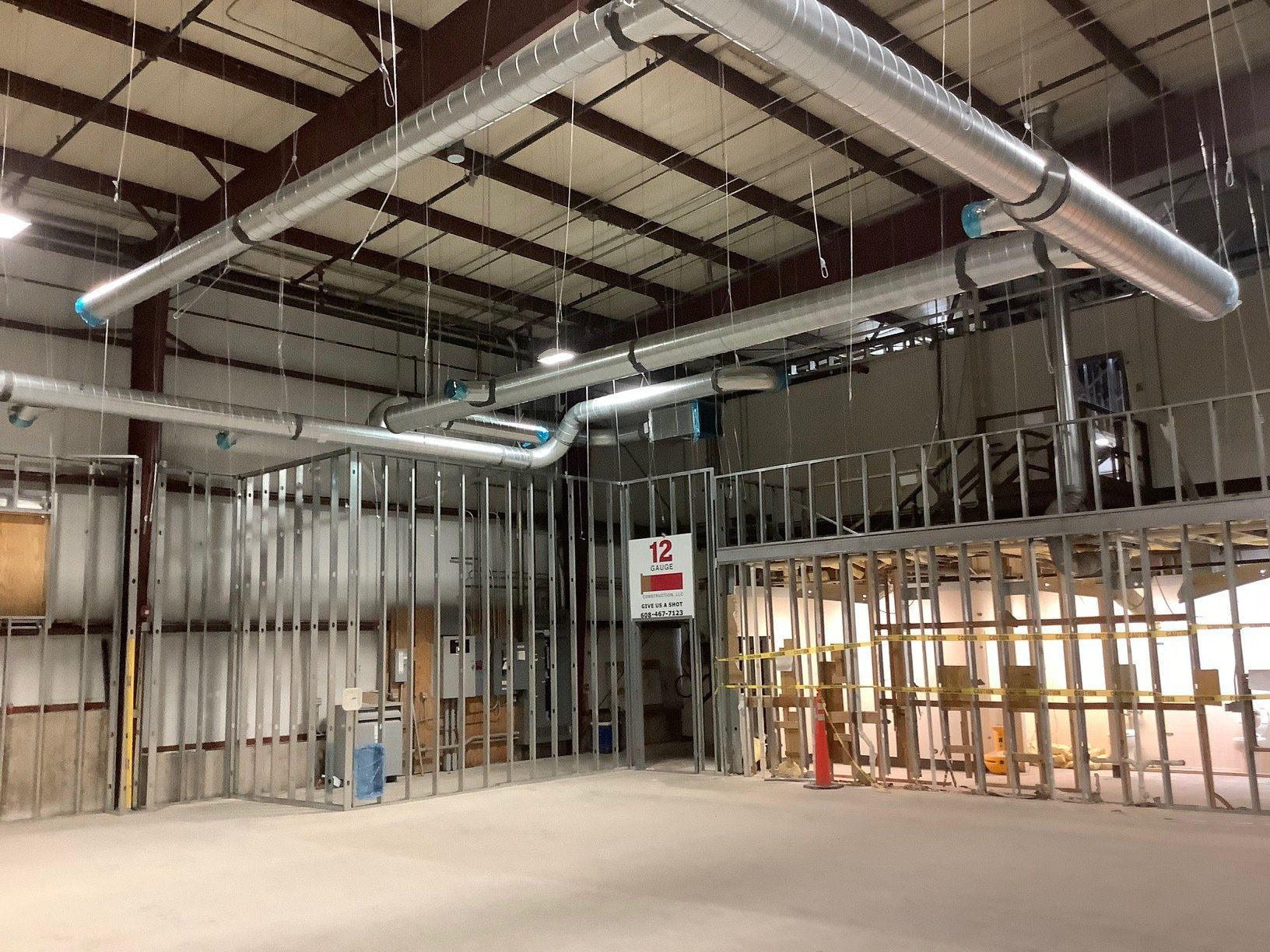 Interior view of a building under construction, with exposed metal framing, ductwork, and concrete floor.