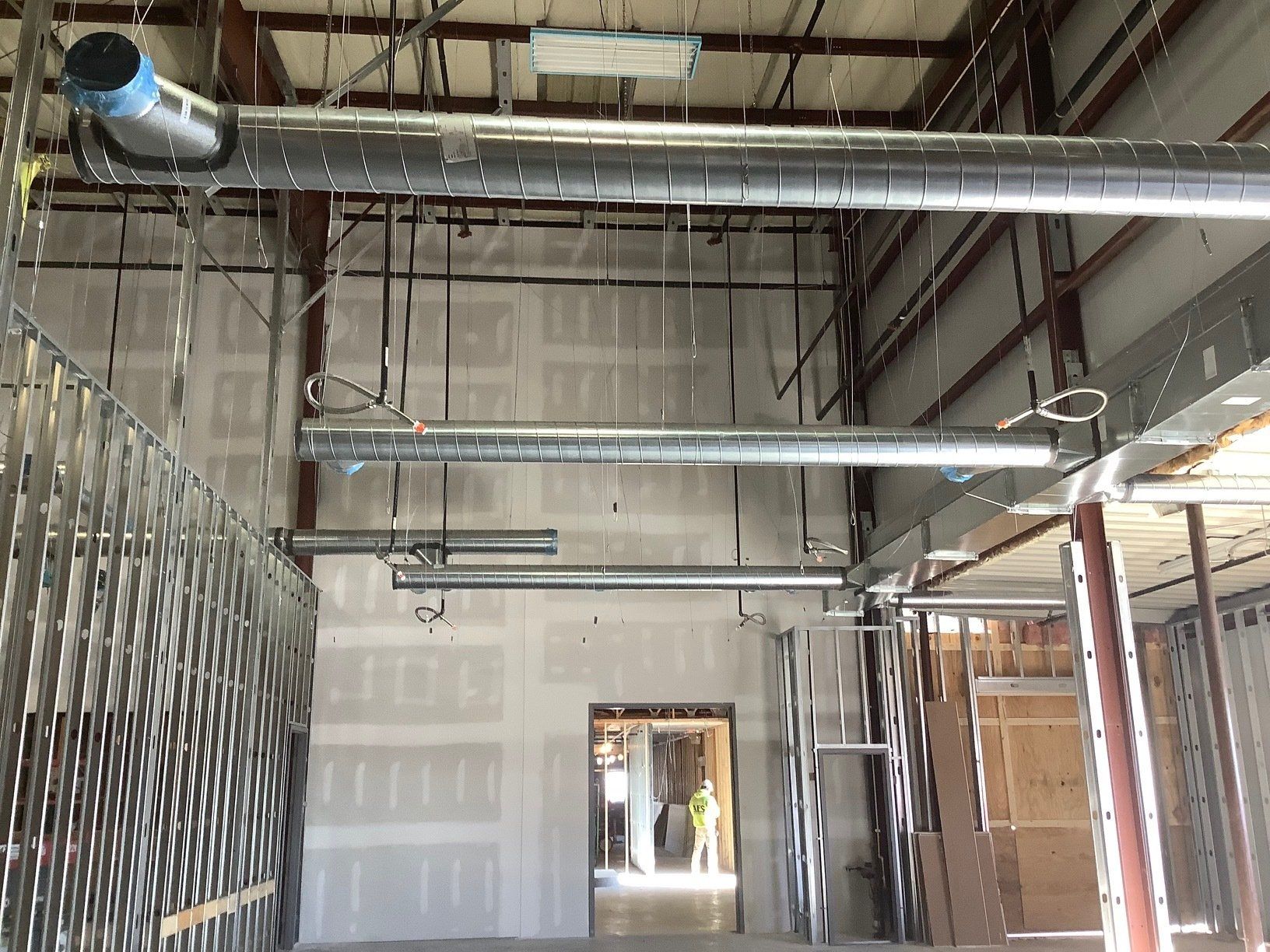 Interior of unfinished building with metal ductwork, steel framing, and drywall.
