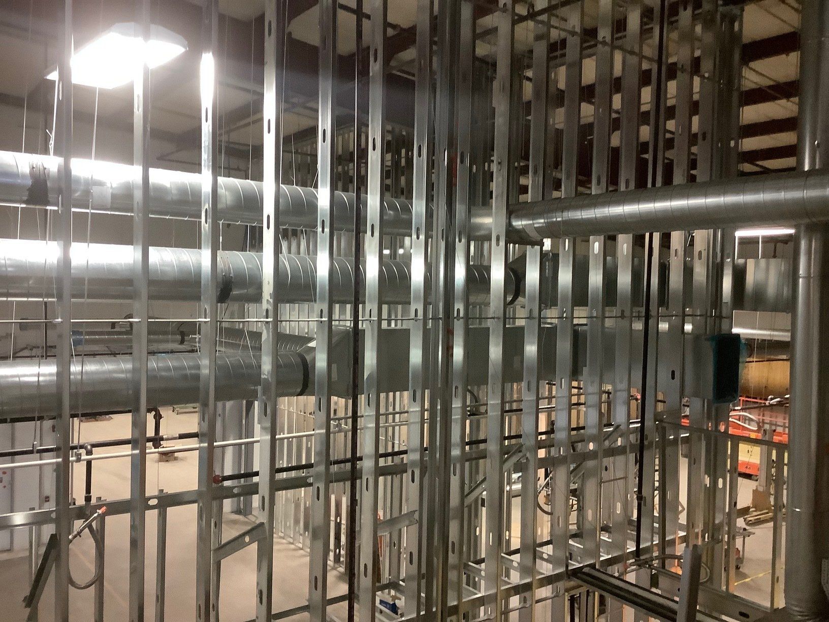 Metal framing and ductwork in an industrial setting, with open metal studs and galvanized pipes.