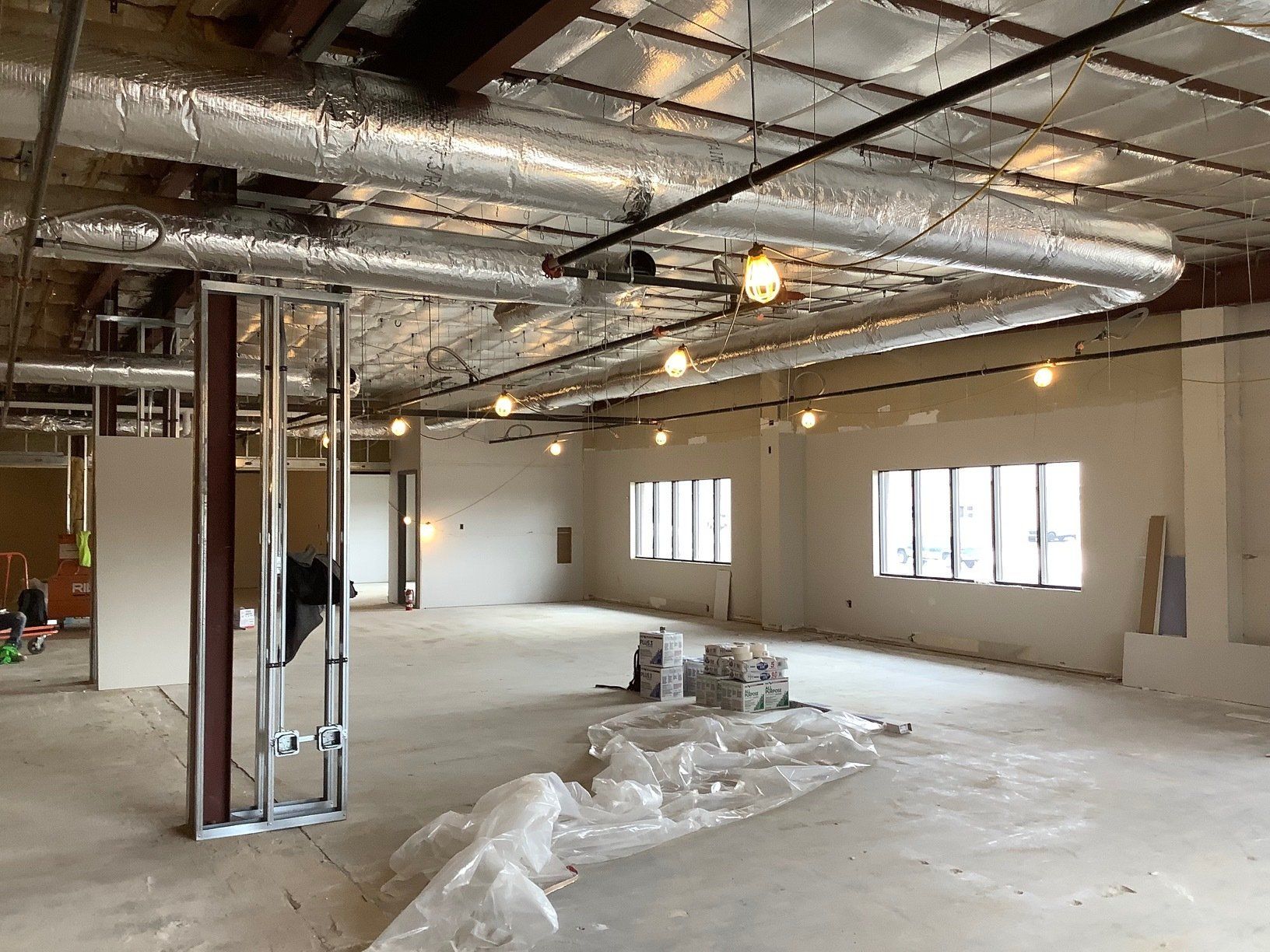 Interior of a building under construction, showing ductwork, exposed framing, and bare walls.