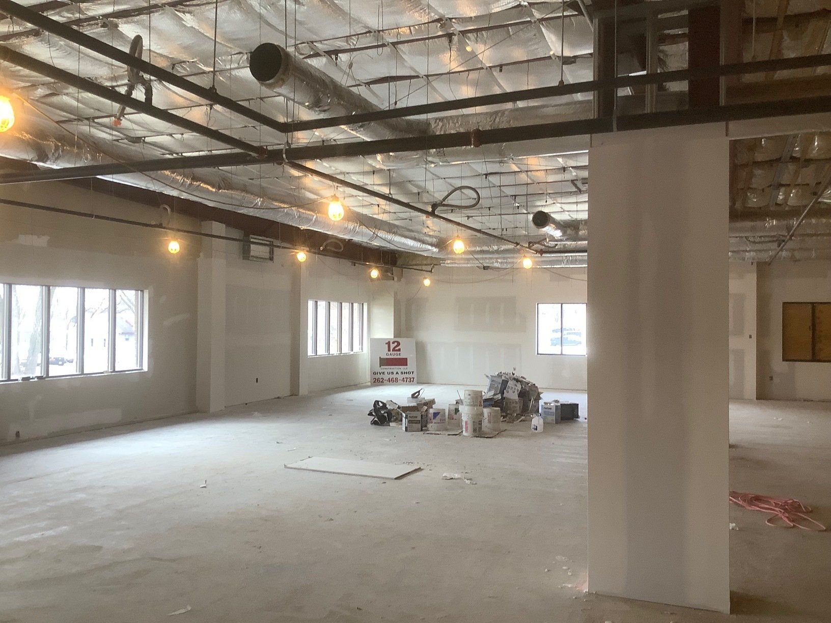 Interior of a building under construction, showing bare walls, exposed ceiling, and construction materials.