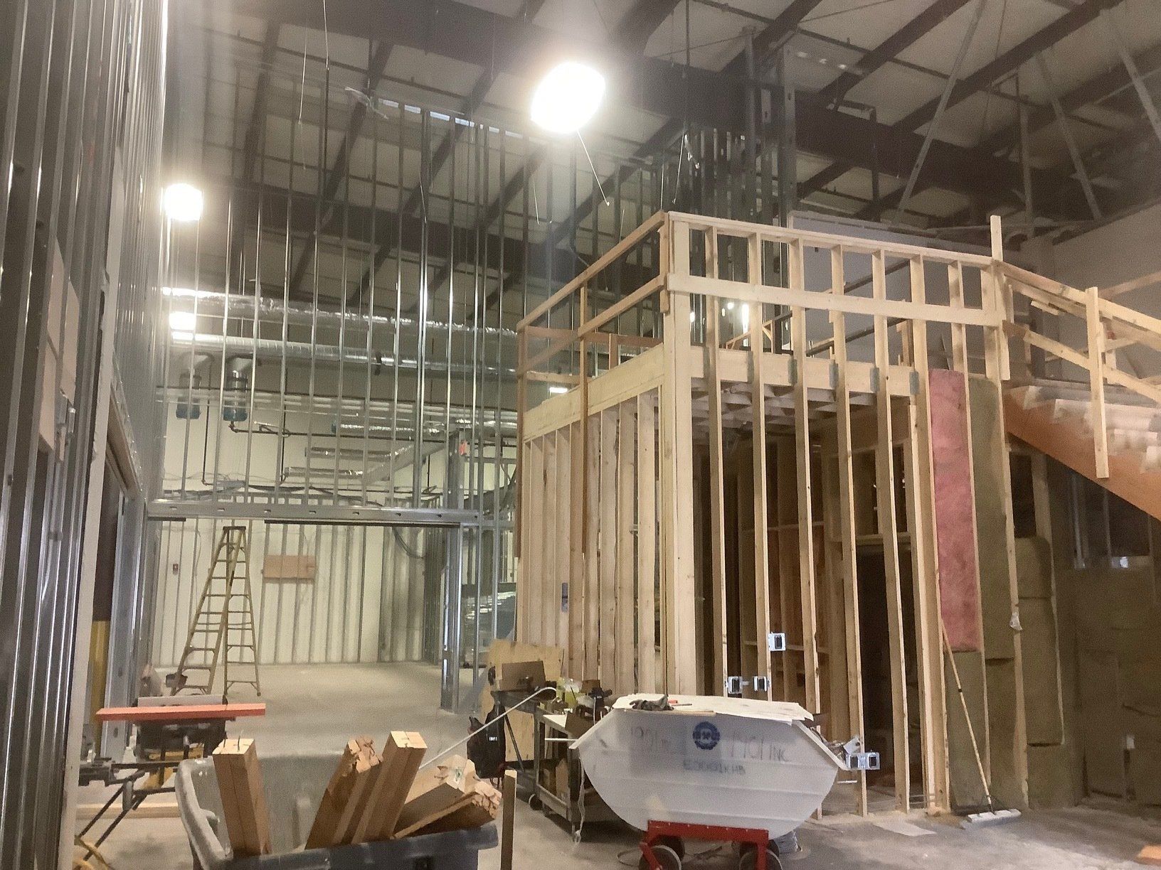 Interior of a building under construction, showing framing, metal studs, insulation, and tools.
