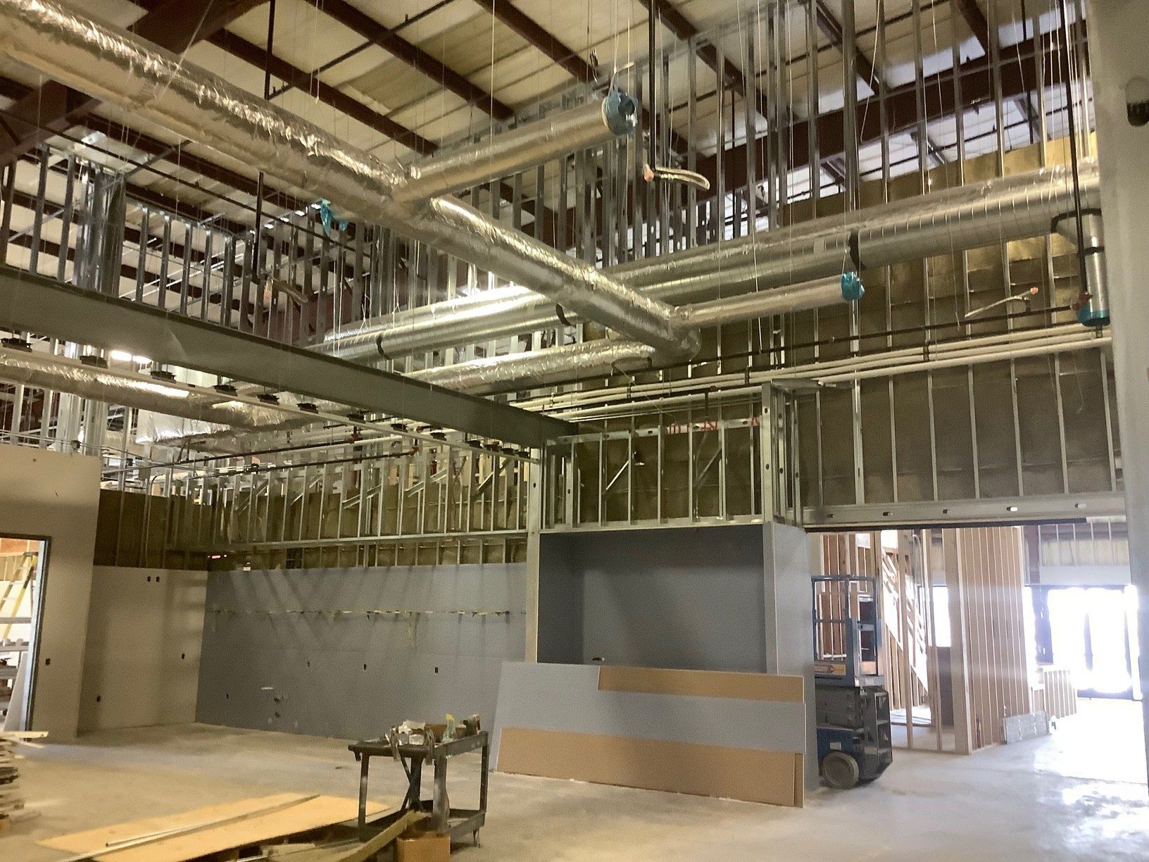 Interior of a building under construction. Exposed ductwork and framing are visible.
