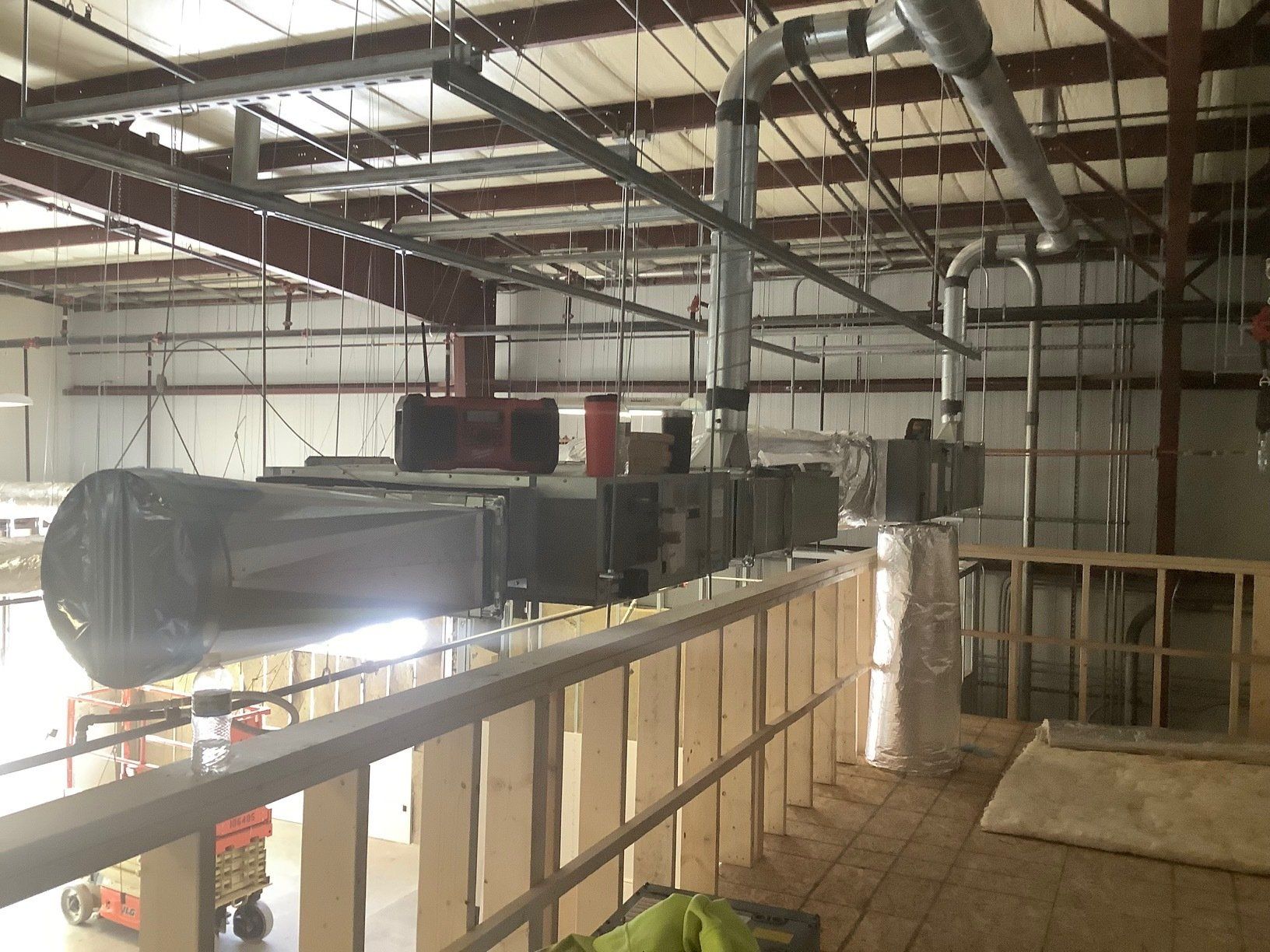 HVAC system installation in an industrial building; ductwork, pipes, and units visible.
