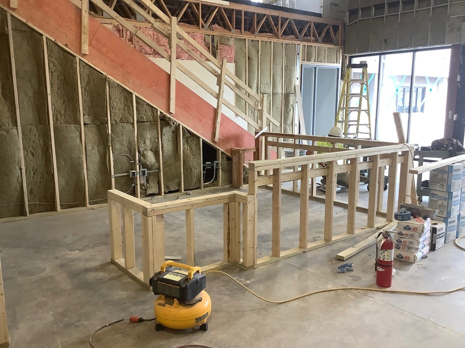 Interior construction site with wooden framing, staircase, and insulation.