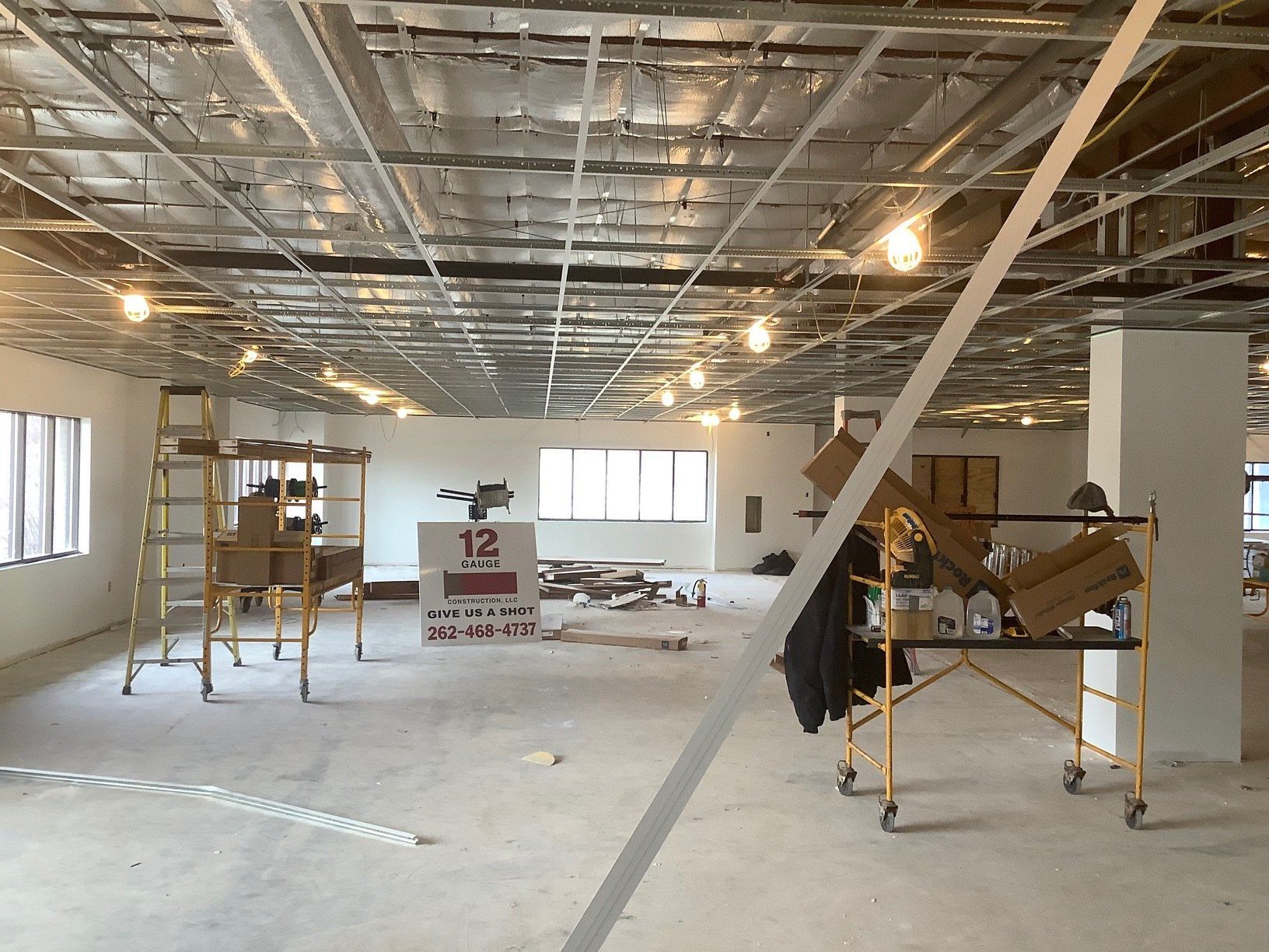 Interior construction site with exposed ceiling, scaffolding, and scattered materials.