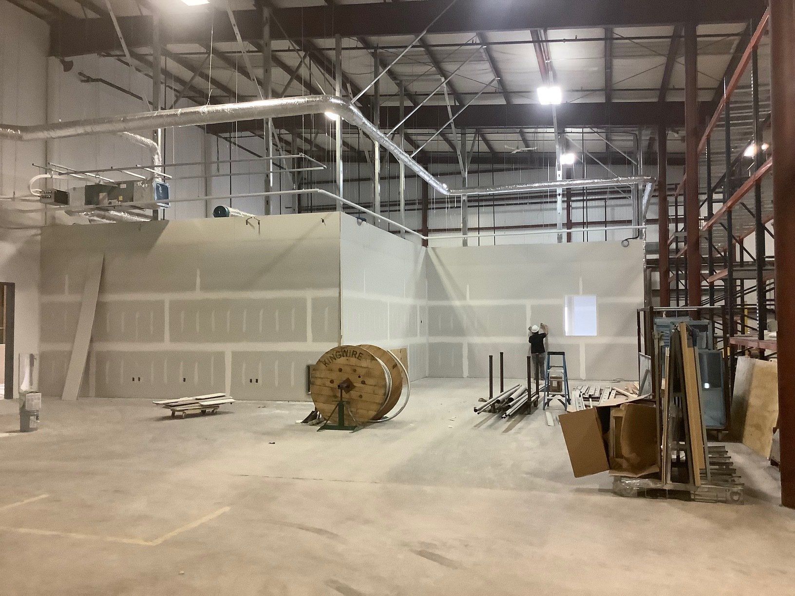 Interior of a construction site with exposed steel beams, drywall walls, and concrete floor.
