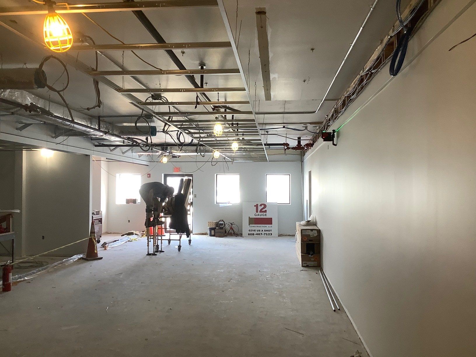 Interior construction site with exposed ceiling, drywall, and workers.