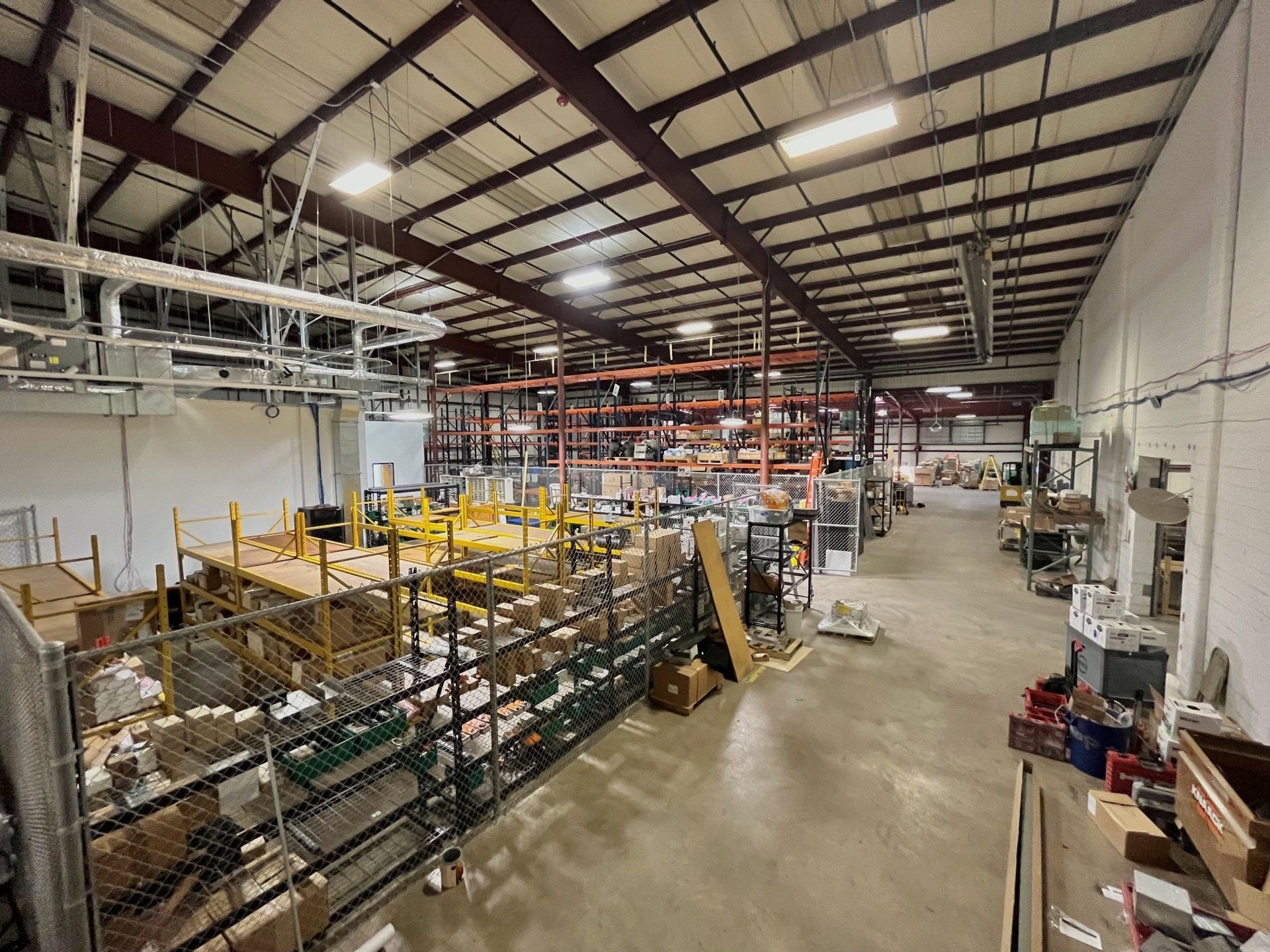Warehouse interior with storage racks, equipment, and scattered materials.