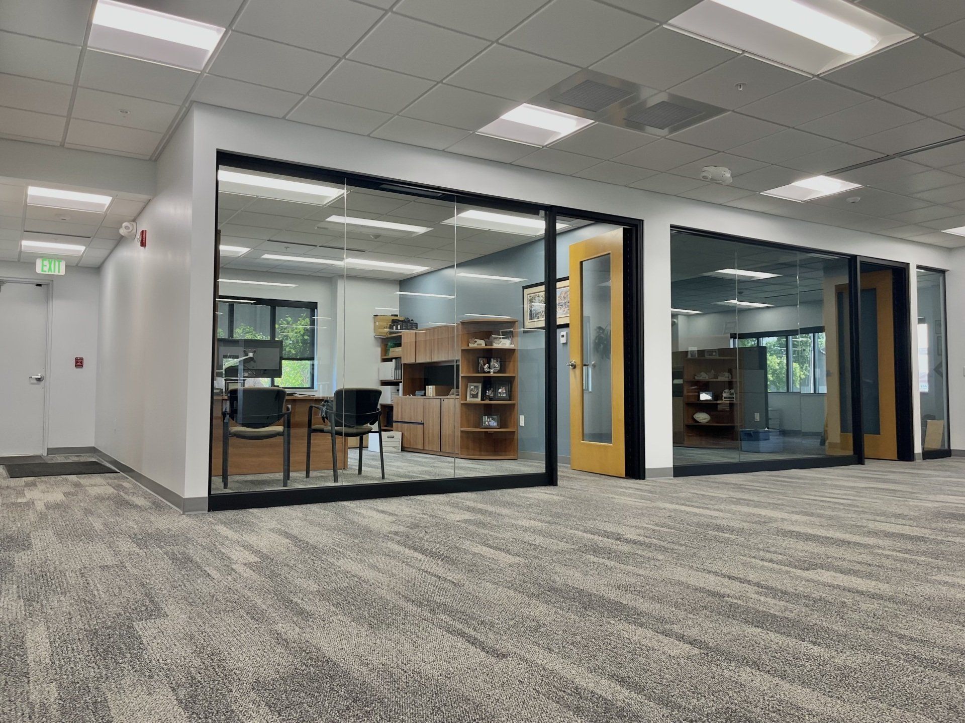 Office interior with glass walls, carpet, and an open doorway.