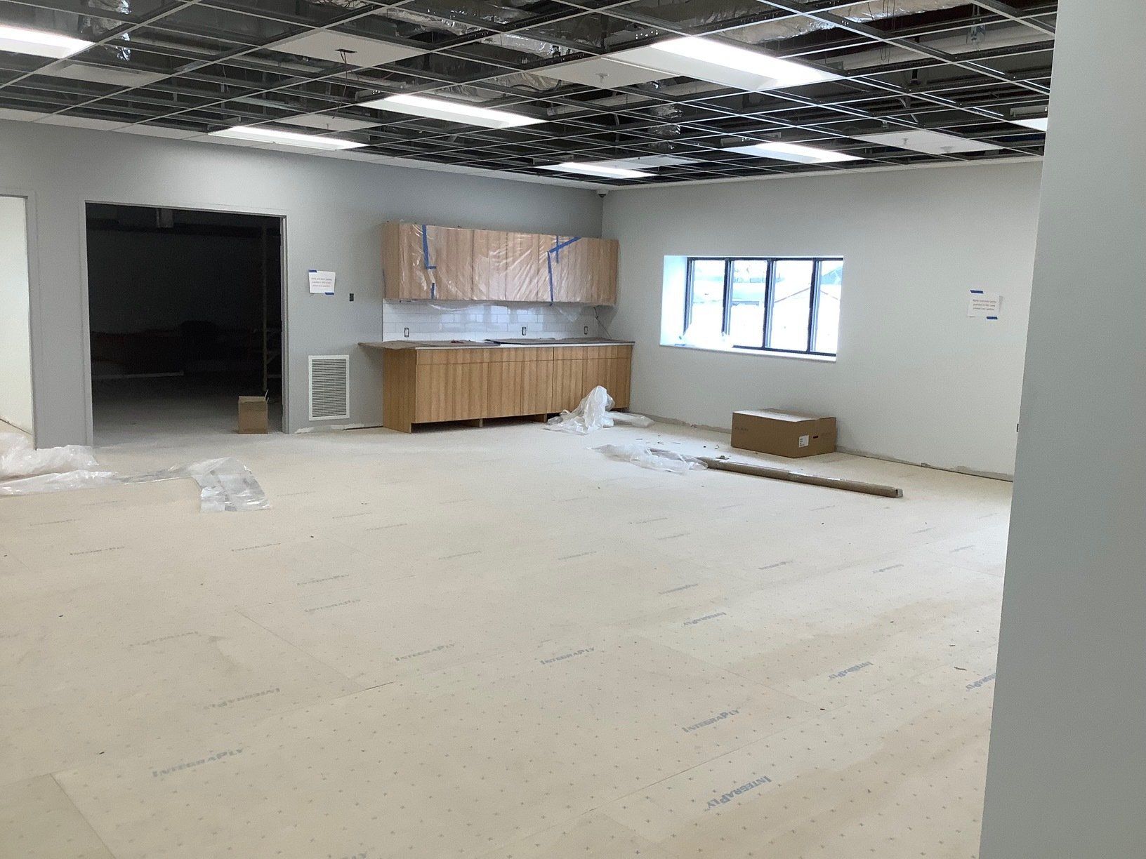 Interior of a room under construction with cabinets, unfinished ceiling, and a doorway.