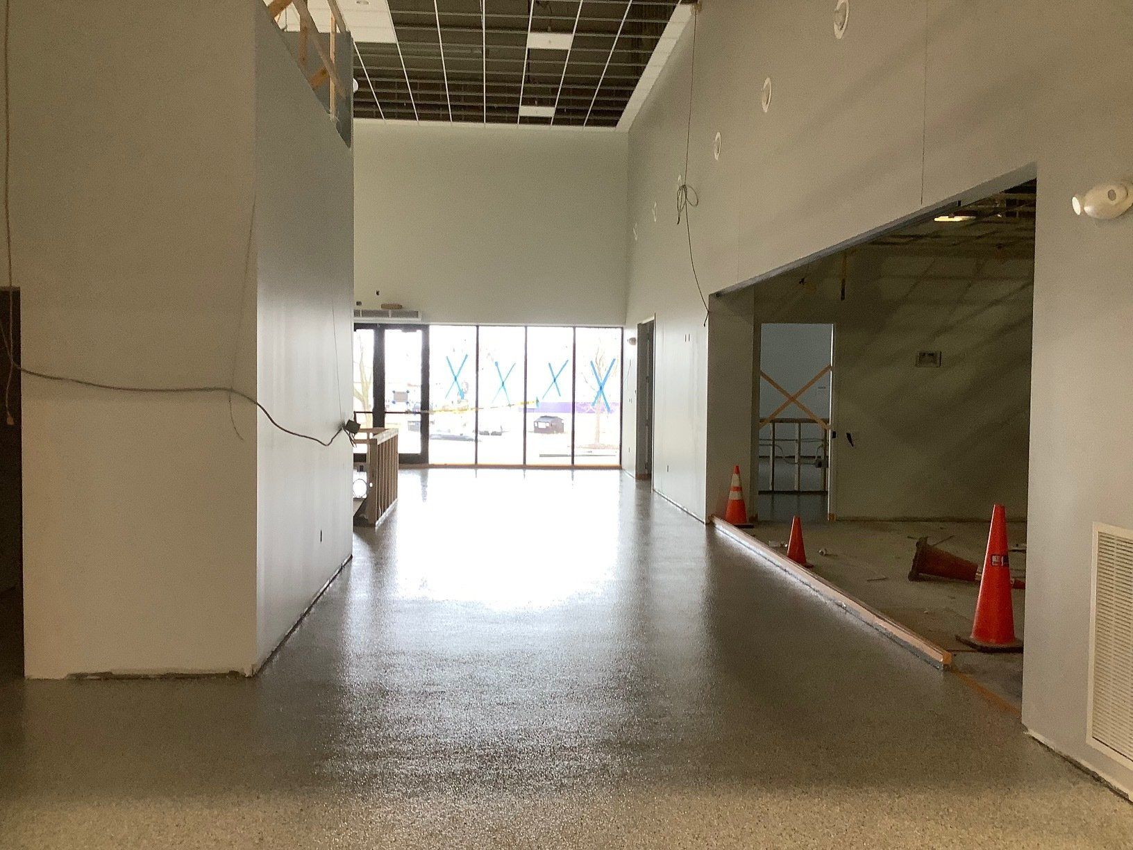 An interior space under construction with polished concrete floors and large windows.
