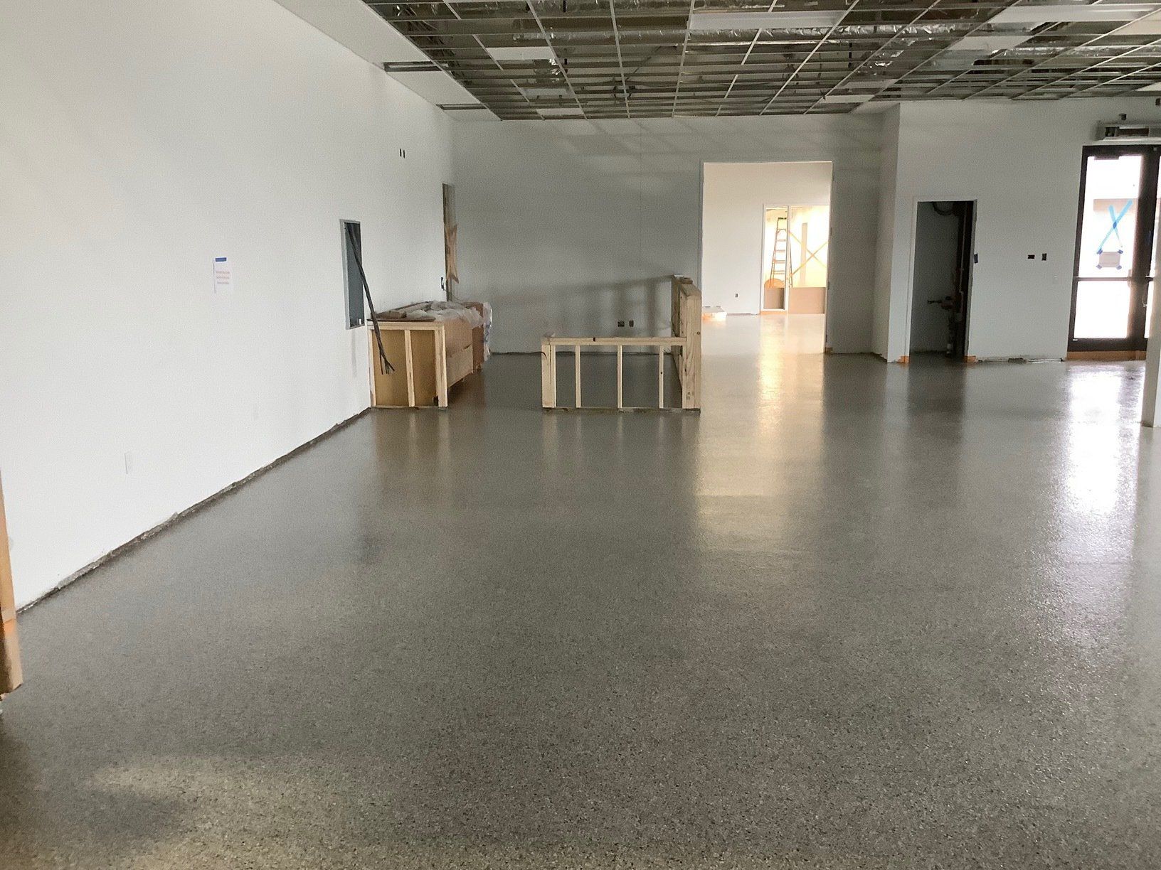 Empty room with polished concrete floor, exposed ceiling, and white walls.