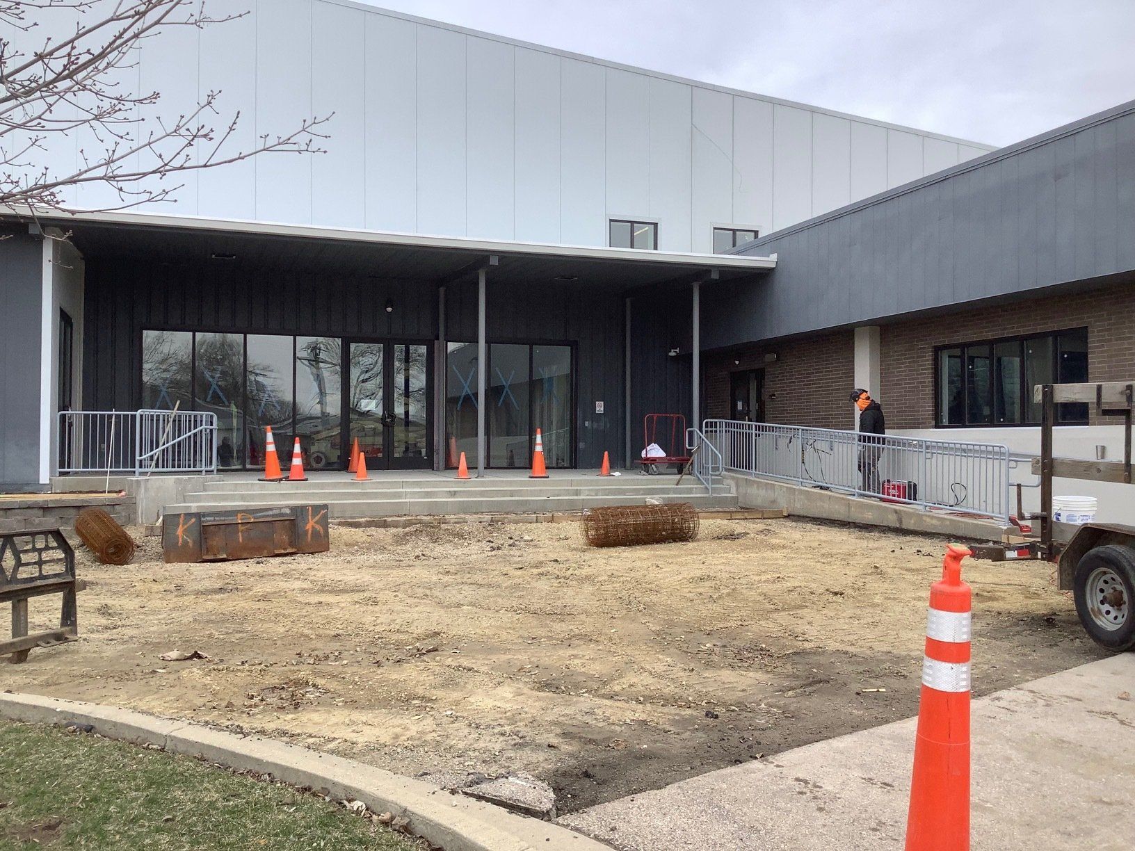 Building exterior with construction; ramp, cones, and dirt foreground.
