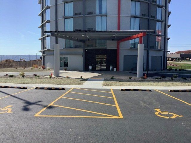 Modern building entrance with canopy, accessible parking spaces marked with wheelchair symbols.