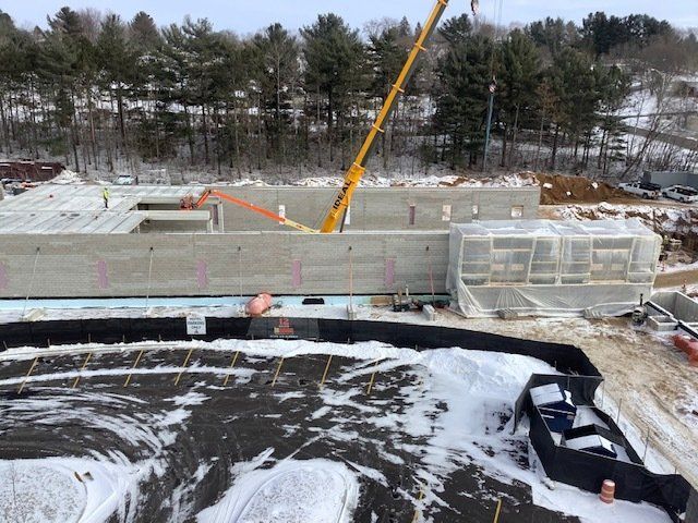 Construction site with a crane lifting concrete walls, winter setting.