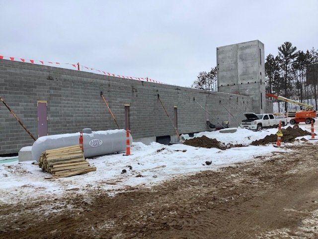 Construction site with cinder block walls, snow, propane tanks, and a truck.