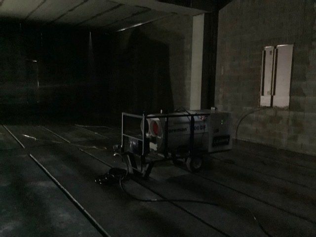 A large, dark industrial space with a machine on wheels and exposed cables.