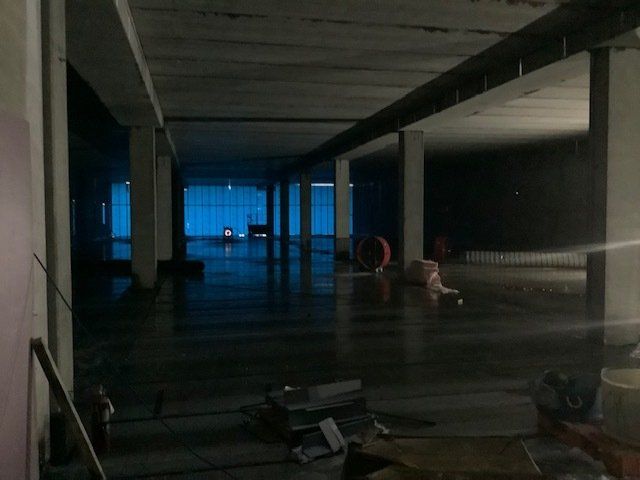 Dark, empty interior with concrete pillars. Blue light glows at the far end.