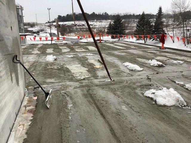 Concrete slab construction; snow patches, orange cones, and worker.