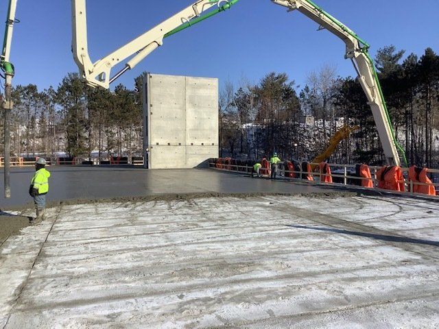 Concrete pouring: A construction site with workers, a concrete wall, and a boom truck pouring concrete over a large surface.