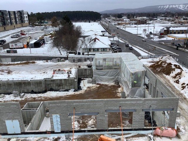 Construction site with a partially built concrete building, snow covered ground.