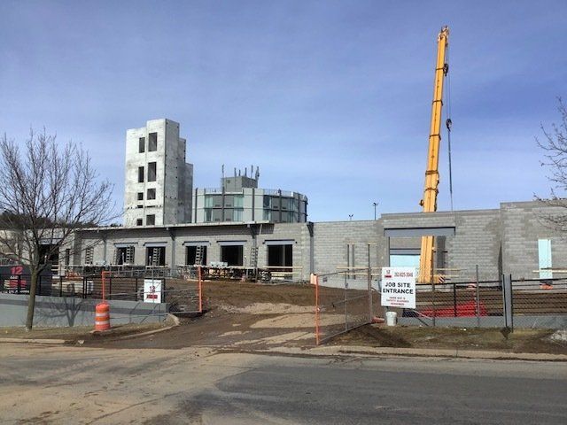 Construction site with concrete block building and tall crane.