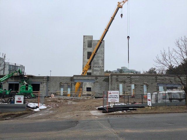 Construction site with crane, partially demolished building, gray sky.