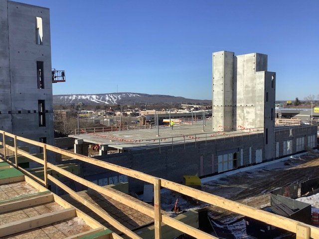 Construction site with concrete structures, a flat roof, and a mountain range in the background.
