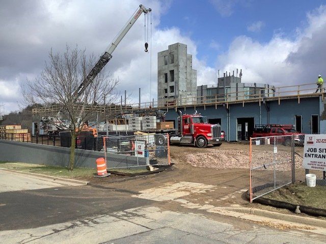 Construction site with a crane, red truck, and workers on a building under construction.