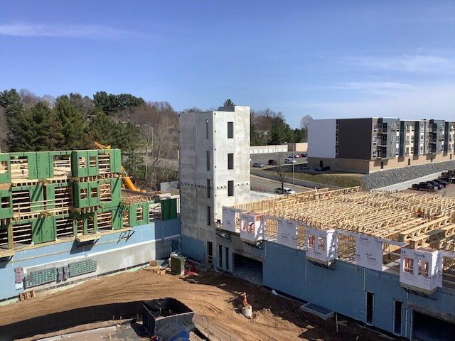 Construction site with building frameworks and unfinished structures against a blue sky.