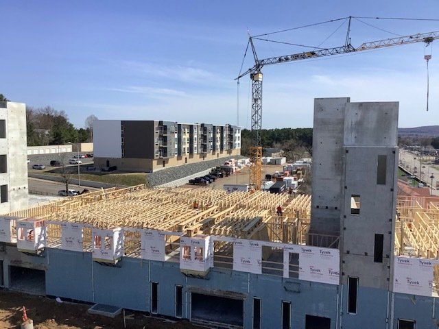 Construction site with a large crane, buildings under construction, blue sky.