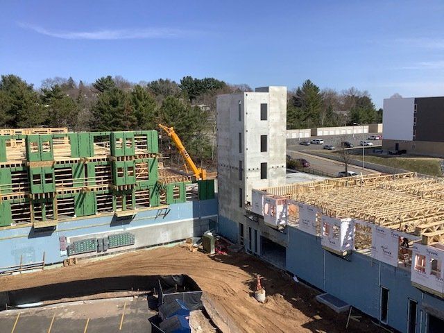 Construction site with wooden framing and concrete tower under blue sky.