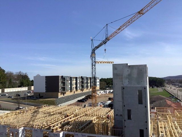 Construction site with crane, partially built buildings, wooden framing, and blue sky.