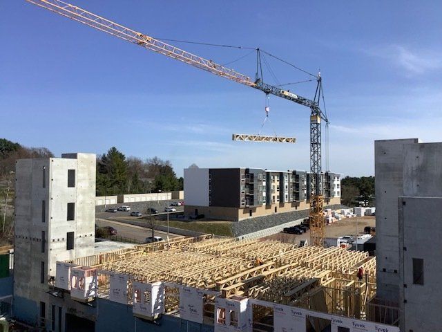 Construction site with crane lifting materials over buildings under construction.