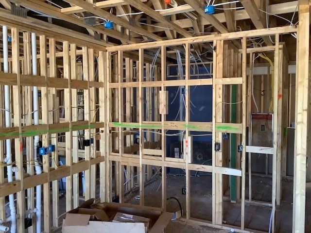 Wooden frame construction of a room, showing electrical wiring and recessed lighting fixtures.