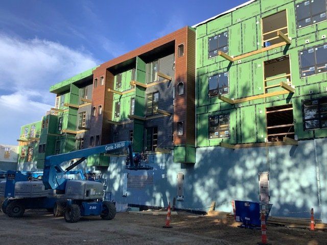 Building construction site with blue lift equipment and a partly finished multi-story structure.