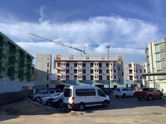 Building construction site with crane and parked vehicles. Blue sky background.