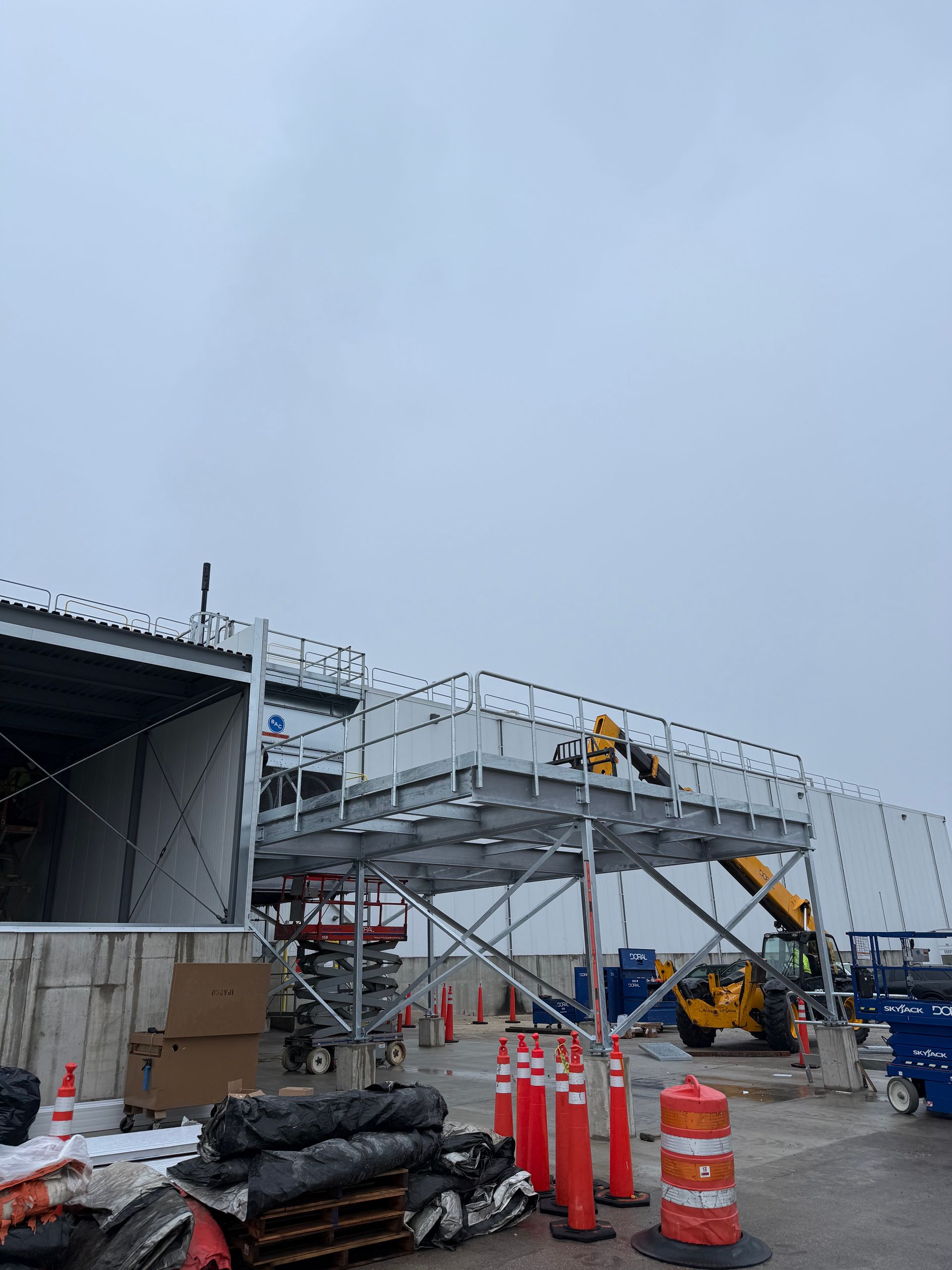 Construction site with scaffolding and a yellow loader under a cloudy sky.