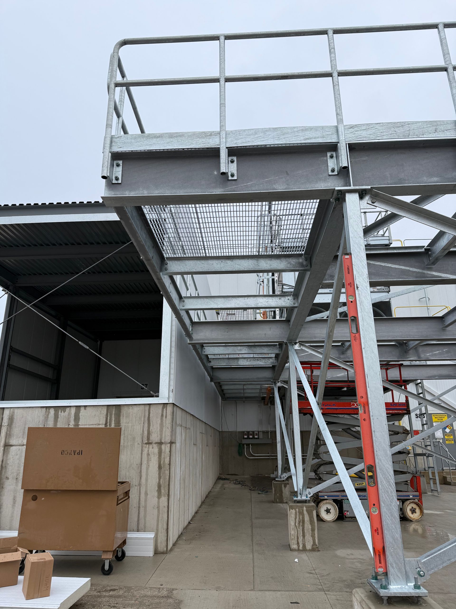 Metal platform and walkway attached to a building, supported by scaffolding.
