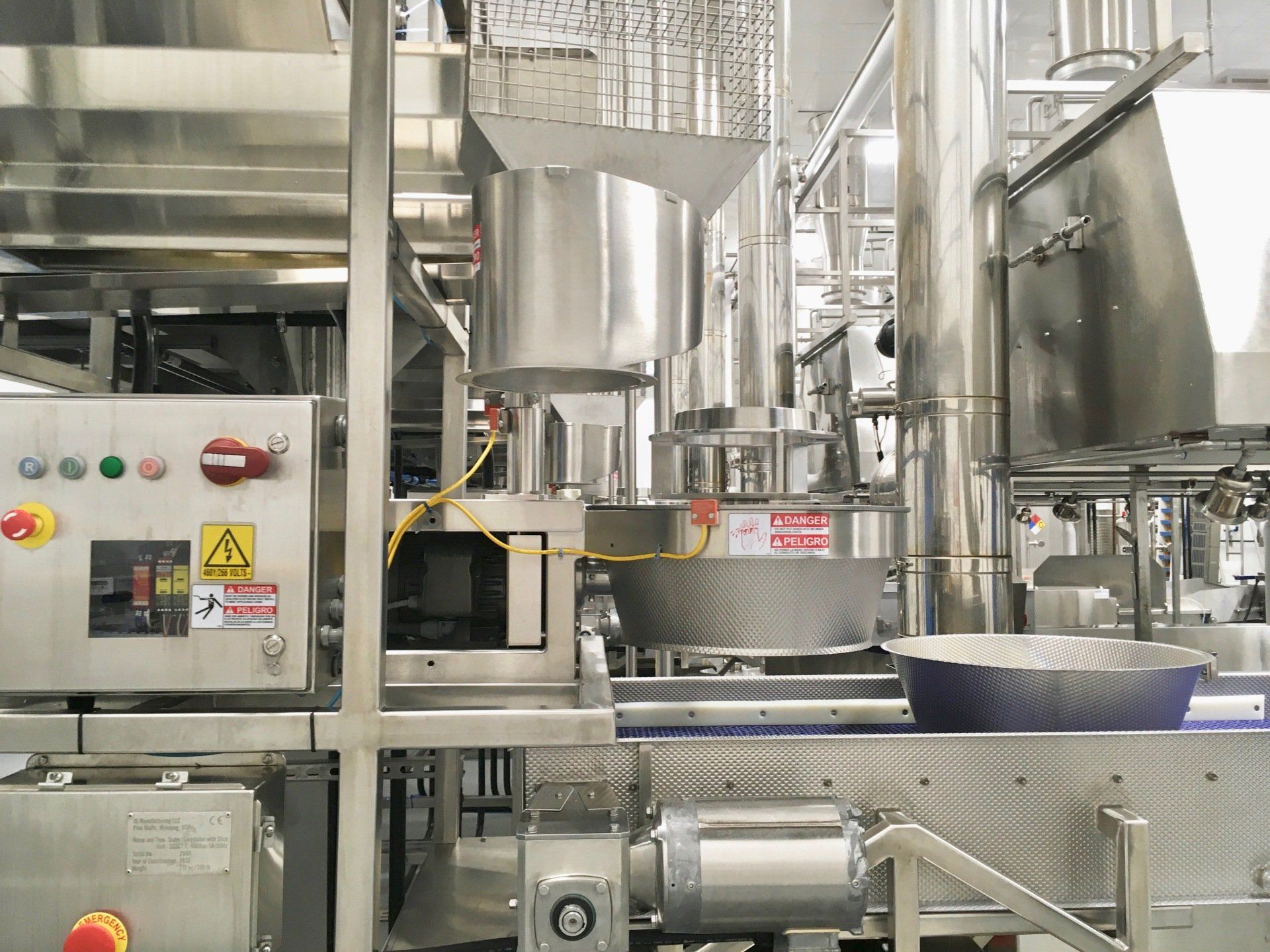 Stainless steel food processing machinery with control panel and conveyor belt.